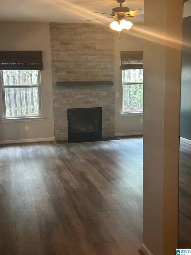 6777 Southern Trace Cir, Leeds, AL 35094 - unfurnished living room with a large fireplace, baseboards, a ceiling fan, and dark wood-style floors