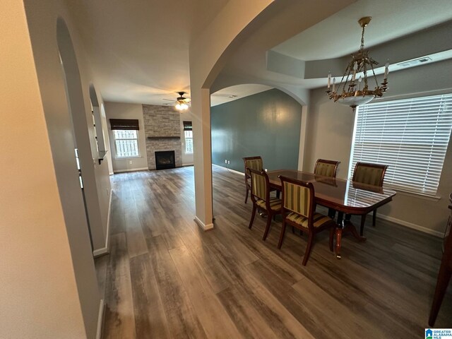 6777 Southern Trace Cir, Leeds, AL 35094 - dining area featuring dark wood-style floors, arched walkways, baseboards, ceiling fan with notable chandelier, and a large fireplace