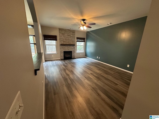6777 Southern Trace Cir, Leeds, AL 35094 - unfurnished living room featuring dark wood-style floors, a ceiling fan, a fireplace, baseboards, and visible vents