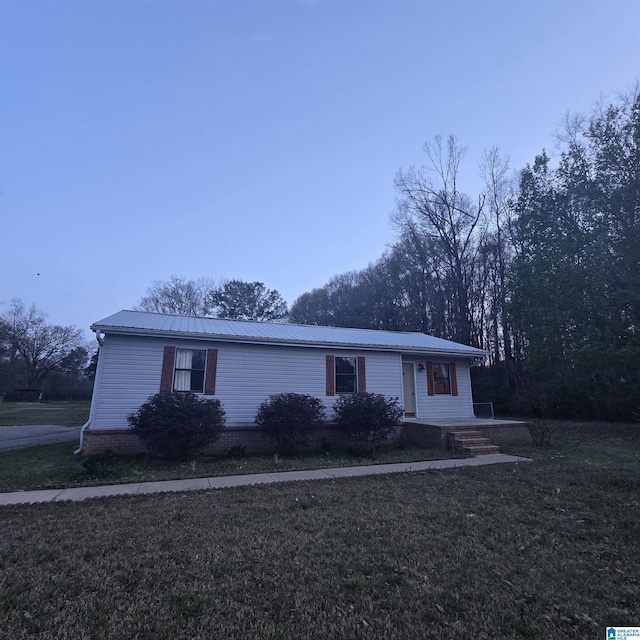 ranch-style home featuring metal roof and a front yard