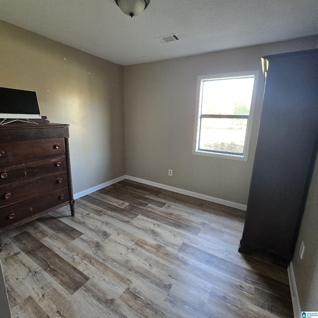 unfurnished bedroom featuring baseboards, visible vents, and wood finished floors