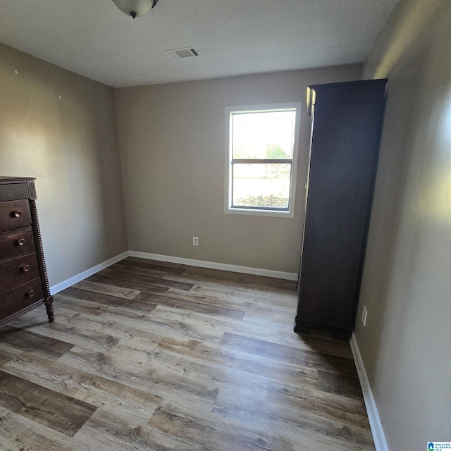 unfurnished bedroom with baseboards, visible vents, and wood finished floors