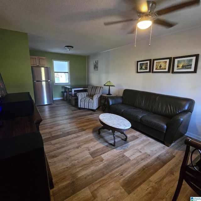 living area featuring dark wood-style floors, baseboards, and a ceiling fan