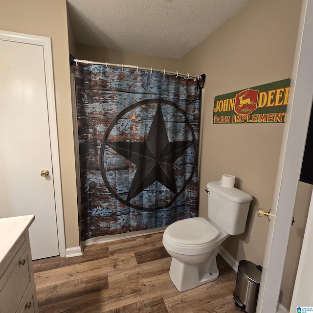bathroom with vanity, curtained shower, toilet, a textured ceiling, and wood finished floors