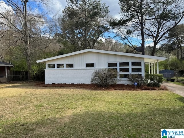 view of home's exterior with brick siding, fence, and a lawn