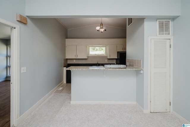kitchen with tasteful backsplash, visible vents, a peninsula, and vaulted ceiling