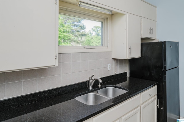 kitchen featuring freestanding refrigerator, a sink, backsplash, and white cabinets