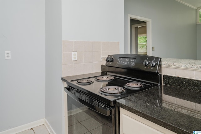 kitchen featuring black electric range oven, tile patterned flooring, backsplash, and dark stone countertops