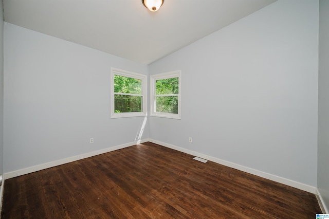 unfurnished room featuring visible vents, baseboards, dark wood-style floors, and lofted ceiling