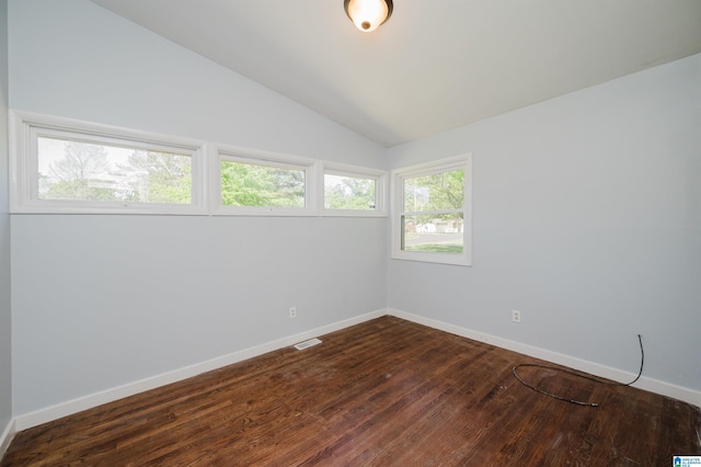 spare room with dark wood-style flooring, visible vents, baseboards, and vaulted ceiling