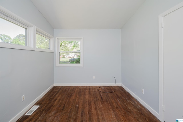 unfurnished room featuring visible vents, baseboards, vaulted ceiling, and wood finished floors
