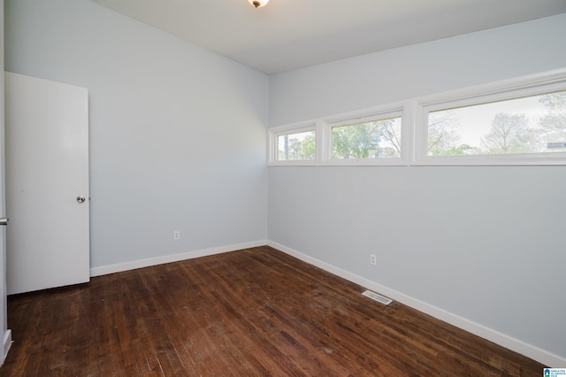 empty room featuring baseboards, wood-type flooring, and visible vents