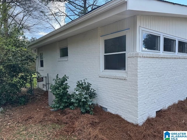 view of home's exterior with crawl space, fence, and brick siding