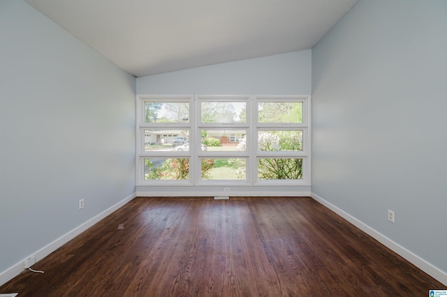 spare room with a wealth of natural light, dark wood-type flooring, baseboards, and lofted ceiling