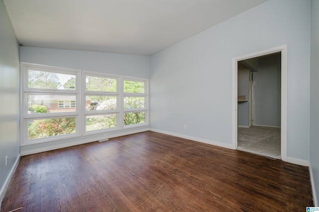 spare room with visible vents, baseboards, plenty of natural light, and dark wood finished floors