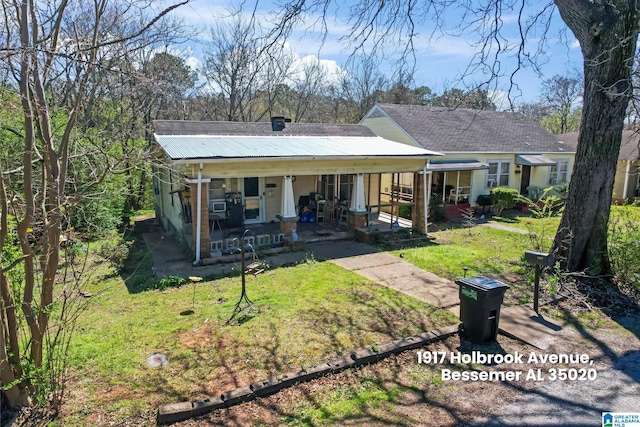 back of property with a porch, metal roof, a yard, and a chimney