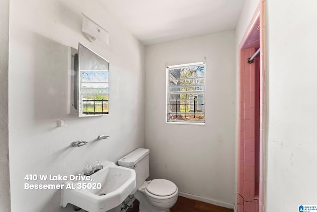 bathroom featuring toilet, a sink, baseboards, and walk in shower