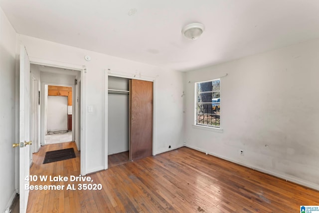 unfurnished bedroom featuring a closet, baseboards, and wood-type flooring