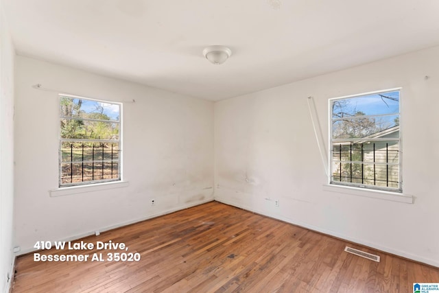 spare room featuring hardwood / wood-style flooring, baseboards, and visible vents
