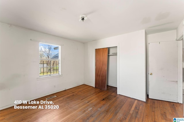 unfurnished bedroom featuring hardwood / wood-style floors, a closet, and visible vents