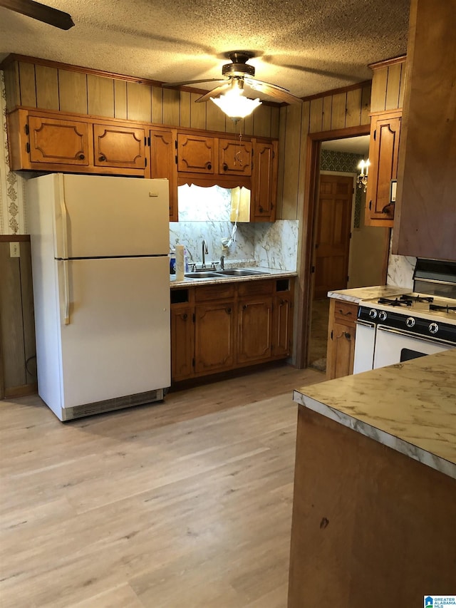 kitchen with ceiling fan, a sink, brown cabinets, and white appliances