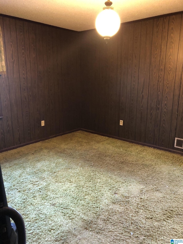 carpeted empty room with wooden walls and visible vents