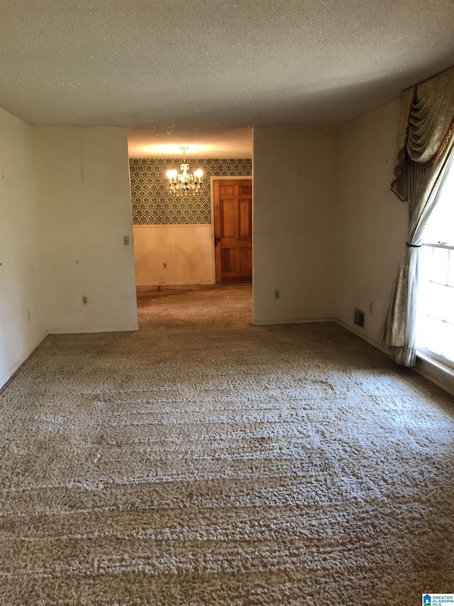 empty room with a chandelier and a textured ceiling
