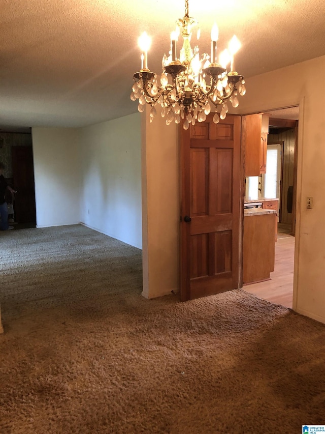 unfurnished dining area with an inviting chandelier, light carpet, and a textured ceiling