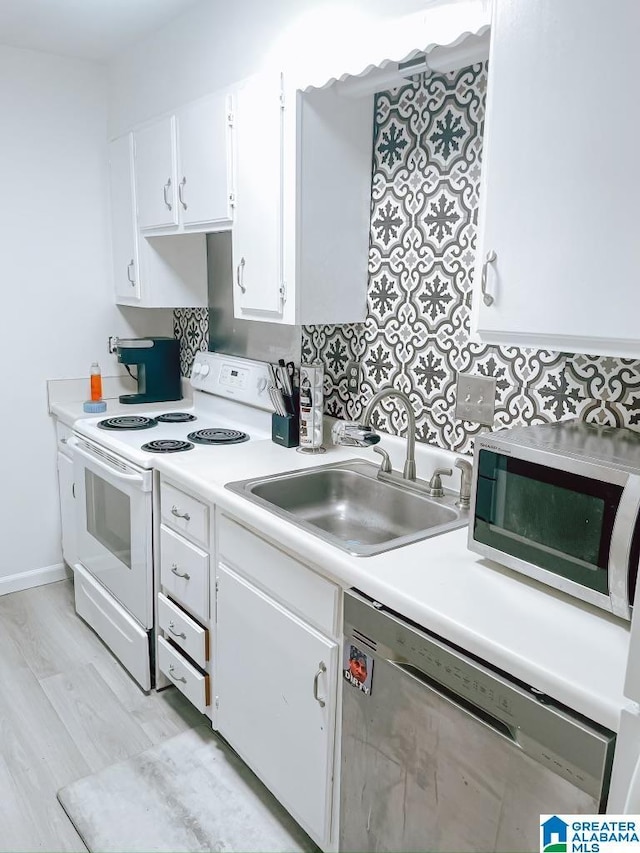 kitchen with white cabinetry, light countertops, stainless steel appliances, a sink, and light wood-style floors