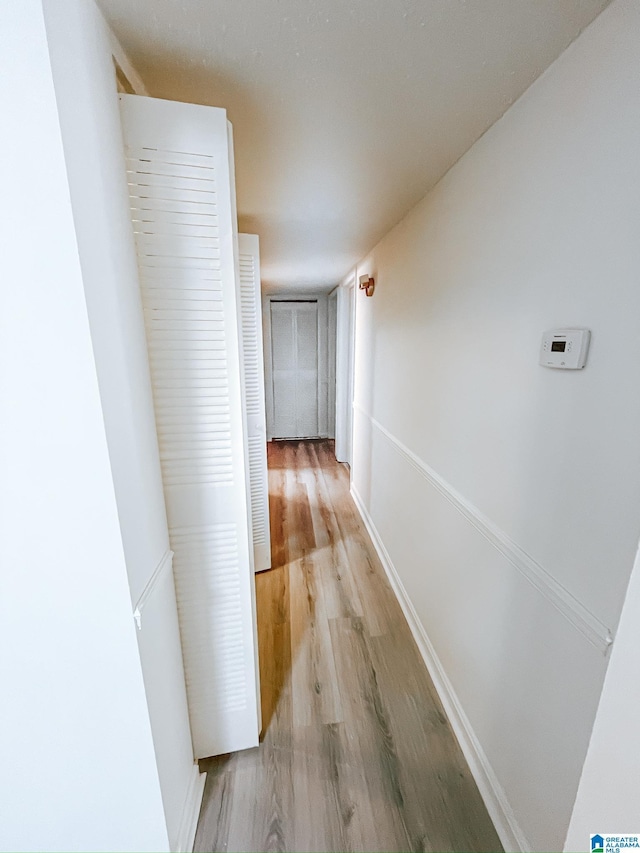 hallway featuring baseboards and light wood-type flooring