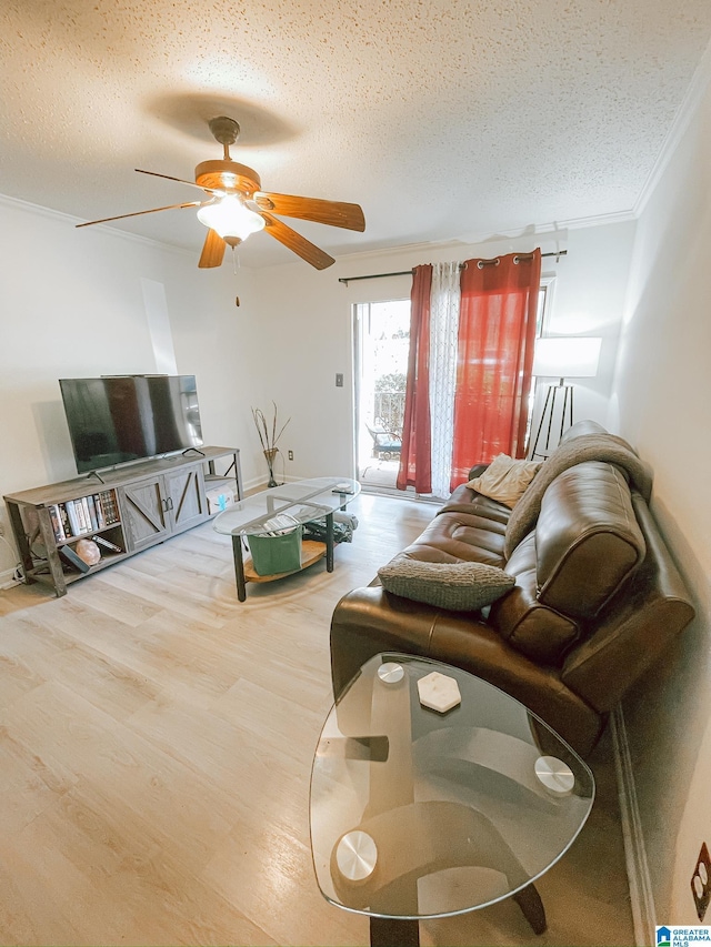 living area with a textured ceiling, a ceiling fan, wood finished floors, and crown molding