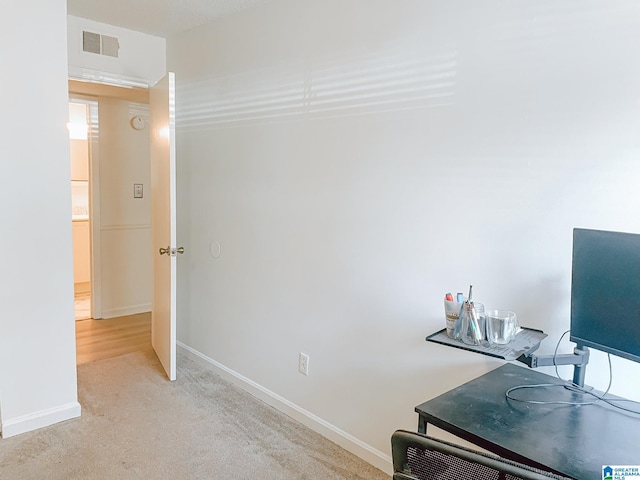 office space featuring baseboards, visible vents, and light colored carpet