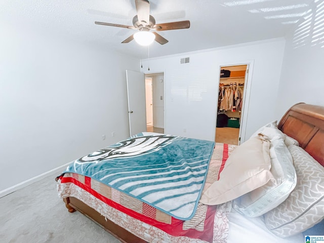 bedroom featuring a spacious closet, baseboards, carpet floors, visible vents, and a ceiling fan