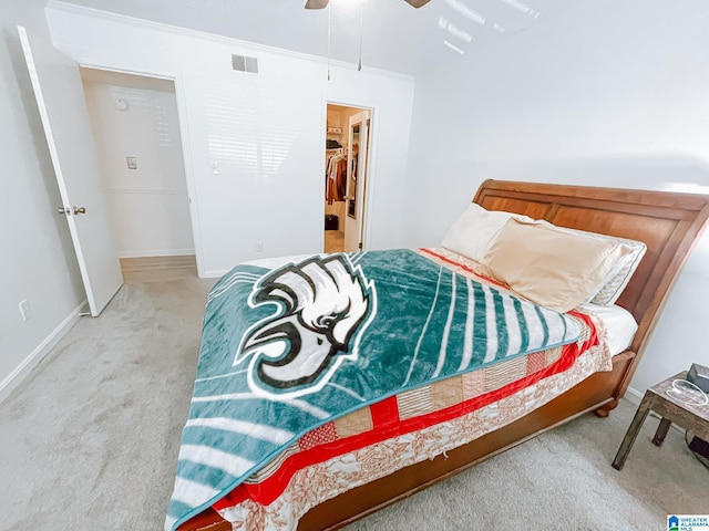 bedroom with a spacious closet, carpet, baseboards, visible vents, and a ceiling fan