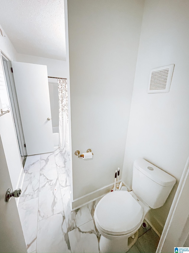 bathroom with toilet, baseboards, a textured ceiling, marble finish floor, and visible vents