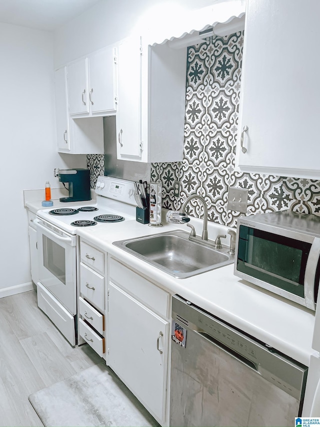 kitchen with light countertops, light wood-type flooring, a sink, white cabinets, and appliances with stainless steel finishes