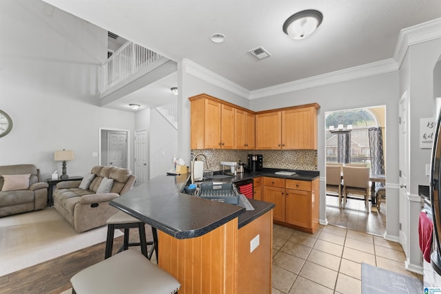 kitchen featuring a peninsula, visible vents, dark countertops, open floor plan, and backsplash