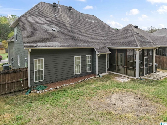 rear view of property with a sunroom, central AC, a yard, fence, and a shingled roof