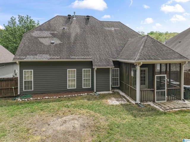 back of property featuring fence, roof with shingles, a sunroom, and a lawn
