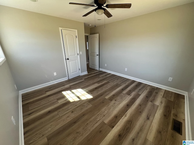 unfurnished bedroom featuring dark wood-style floors, visible vents, ceiling fan, and baseboards