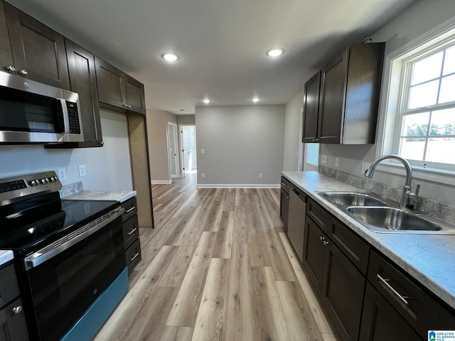 kitchen with light countertops, a sink, appliances with stainless steel finishes, light wood-style floors, and recessed lighting