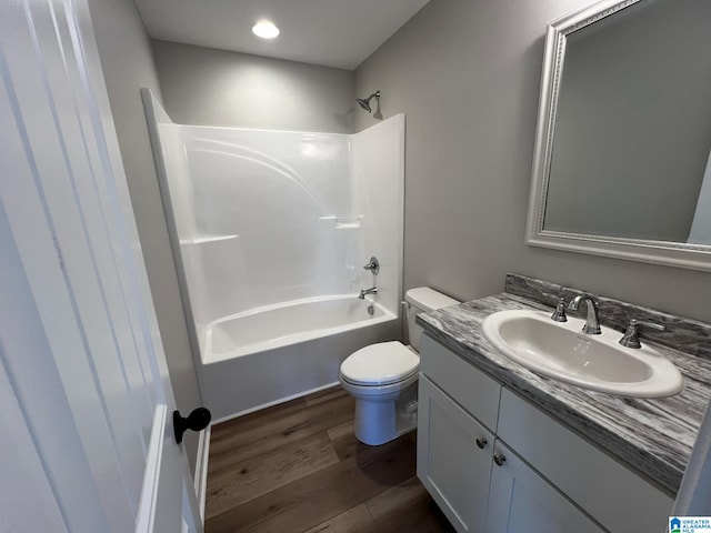 bathroom featuring washtub / shower combination, toilet, wood finished floors, and vanity