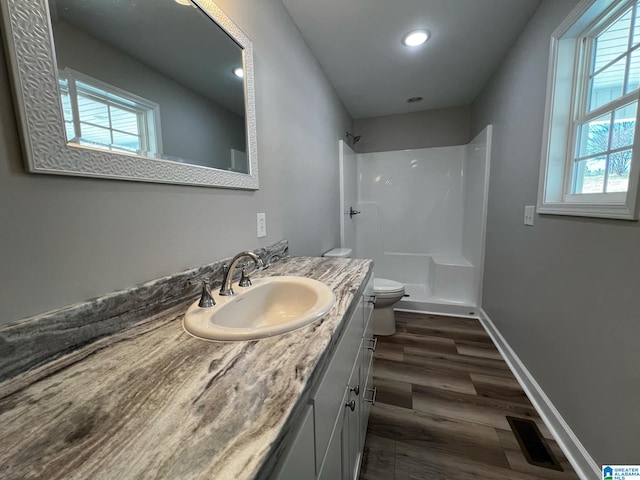 bathroom featuring toilet, a shower, vanity, baseboards, and visible vents