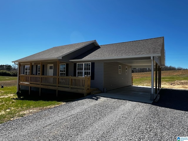 view of front of house featuring driveway, an attached carport, and roof with shingles