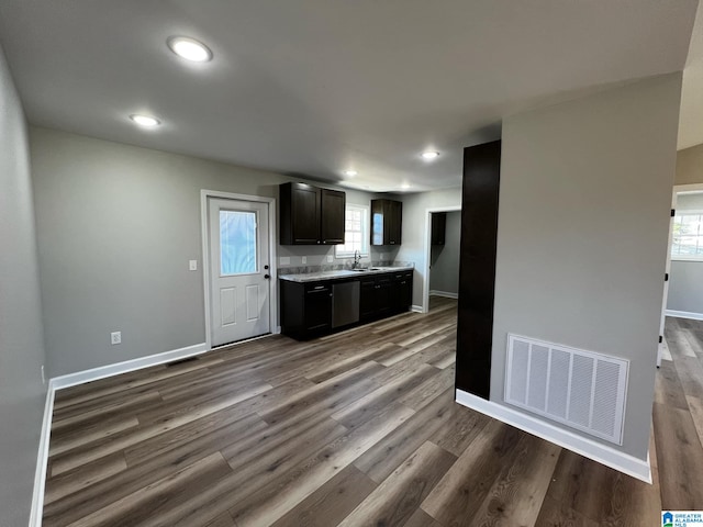 kitchen featuring light countertops, a sink, dark wood-style floors, visible vents, and dishwasher