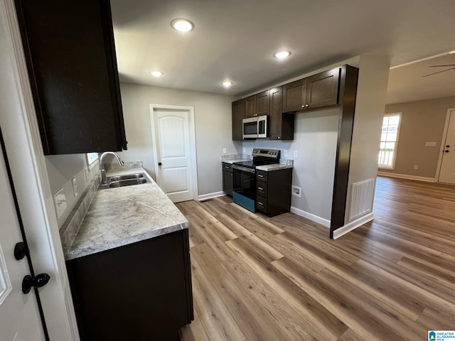kitchen with light countertops, baseboards, a sink, light wood-style flooring, and appliances with stainless steel finishes