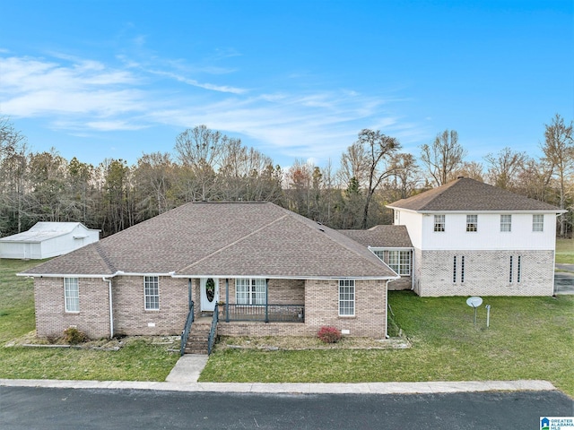 view of front of property featuring brick siding, roof with shingles, a porch, and a front yard