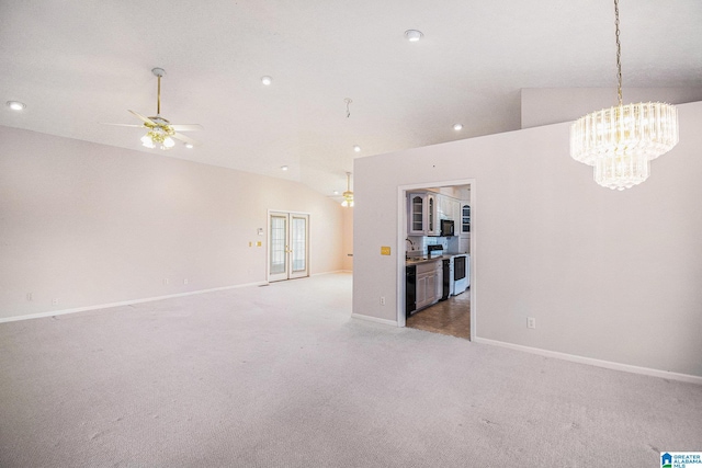 unfurnished living room with vaulted ceiling, light colored carpet, ceiling fan with notable chandelier, baseboards, and a sink