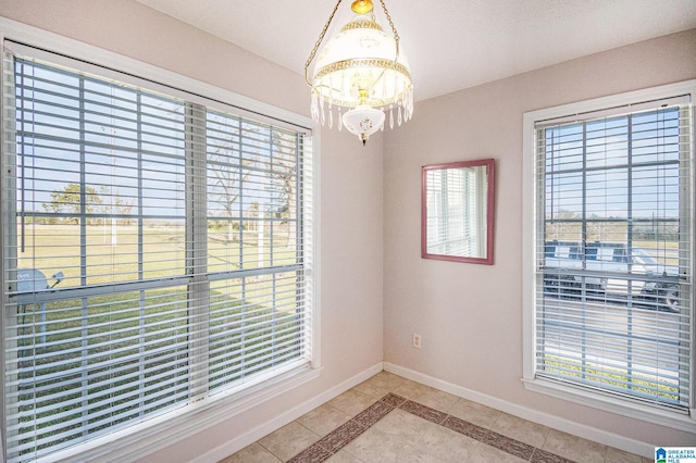unfurnished room featuring light tile patterned flooring, baseboards, and a notable chandelier