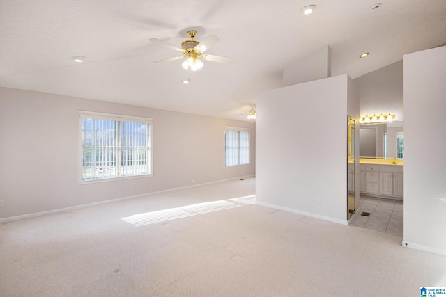 unfurnished bedroom featuring high vaulted ceiling, light carpet, ensuite bath, baseboards, and recessed lighting
